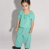 4 year old girl standing wearing a matching top and pants in teal denim polka dot