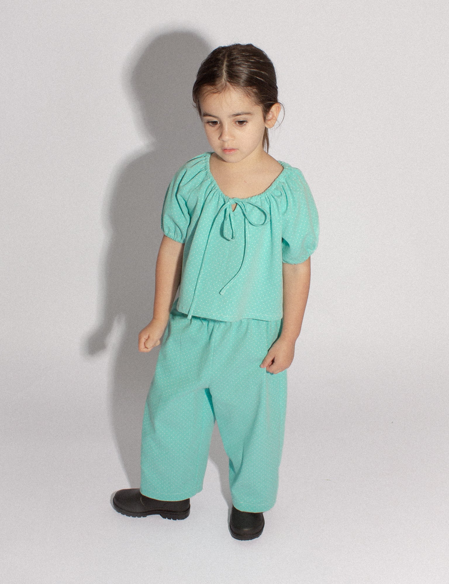 4 year old girl standing wearing a matching top and pants in teal denim polka dot
