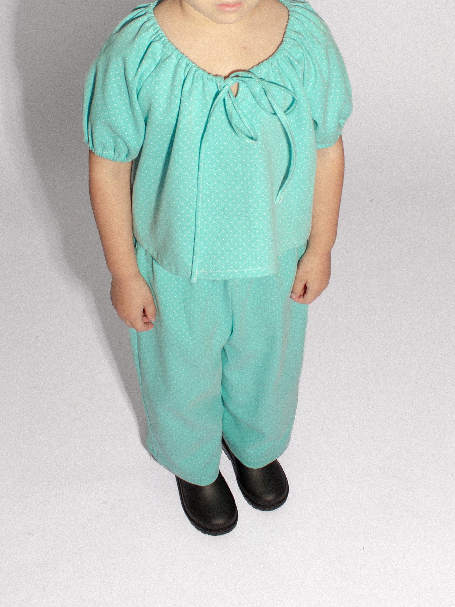 4 year old girl standing wearing a matching top and pants in teal denim polka dot
